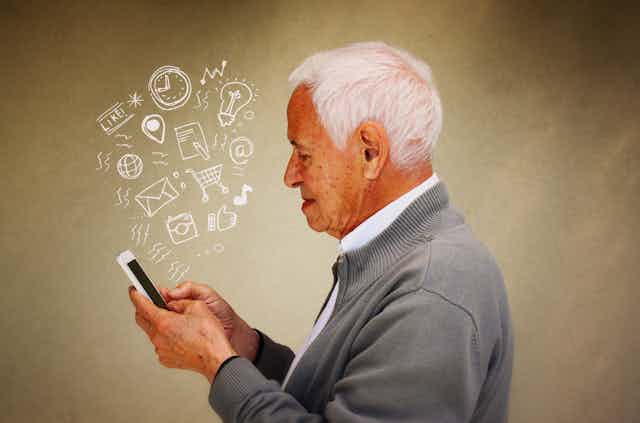 Older man looking at a smart phone with lots of symbols relating to connectivity coming out of it.