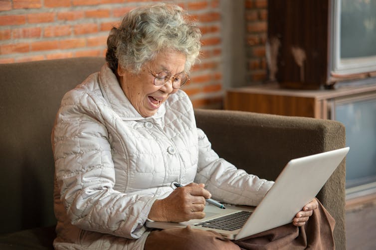 An older black women on her laptop smiling and looking happy.