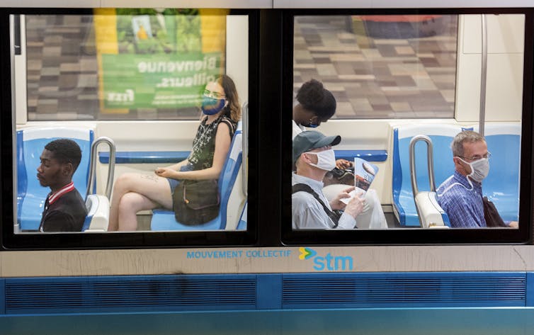 People sit on a Montreal metro wearing face masks