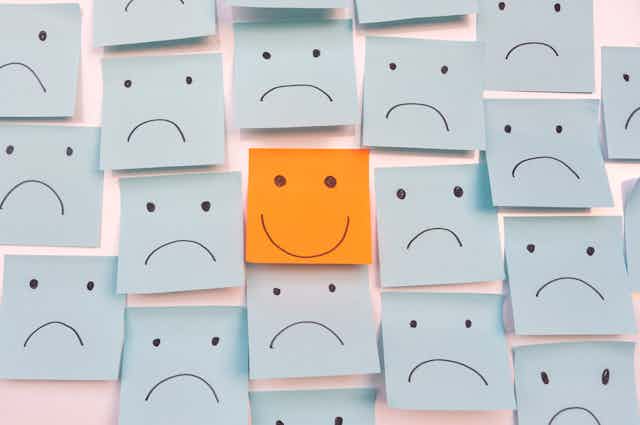 Smiley face surrounded by illustrations of sad faces