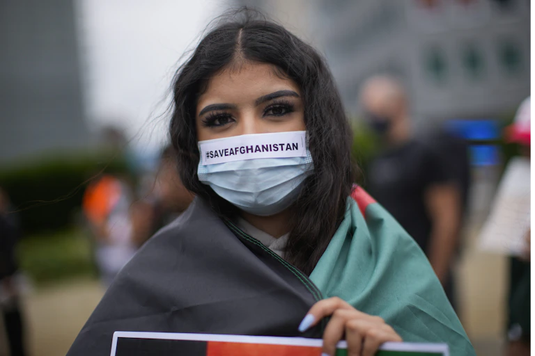 A woman wears a protective face mask reading #SAVEAFGANISTAN during a protest