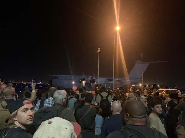A crowd boarding a nighttime flight.