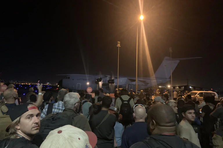 A crowd boarding a nighttime flight.