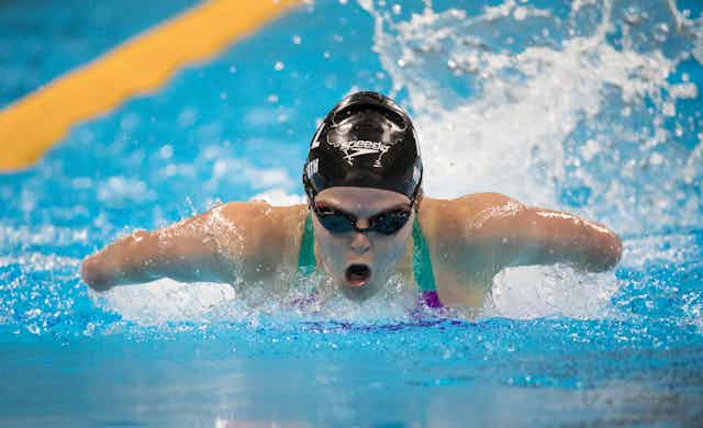 A swimmer emerges from the water with her mouth open