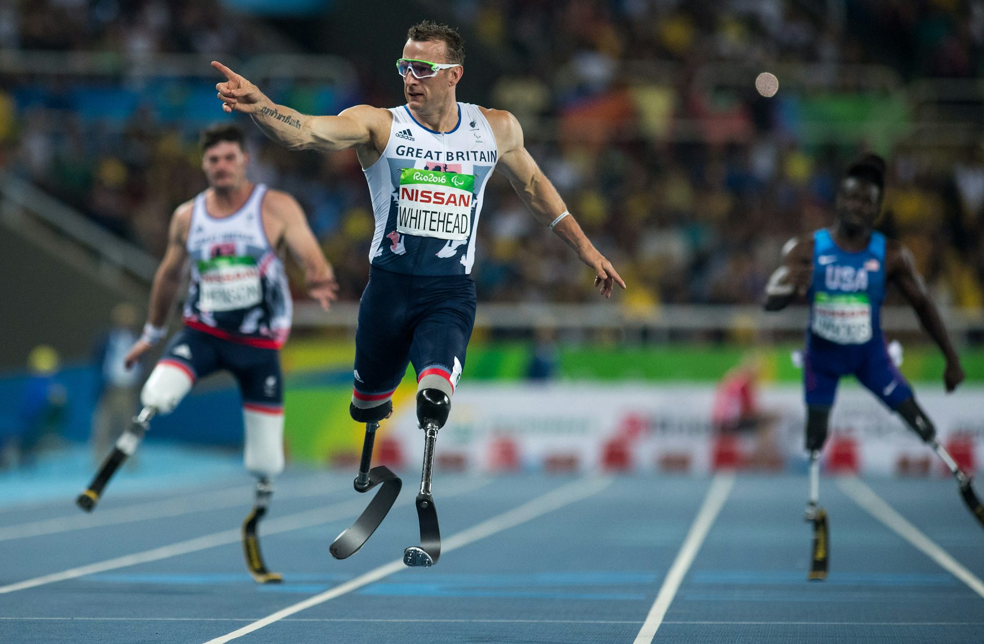 A sprinter points with his right hand after crossing the finish line.