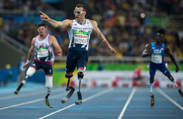 A sprinter points with his right hand after crossing the finish line.