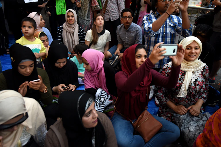 Muslims of all ages gather in a crowd as some take pictures
