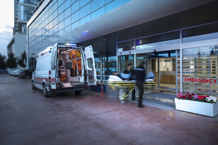 Two medical workers bringing a patient on a stretcher into a hospital.