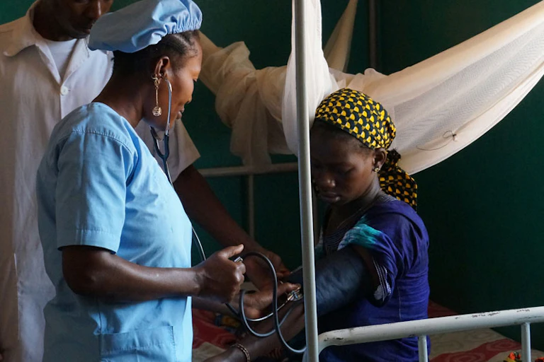 Une jeune femme noire avec un nourrisson et deux travailleurs en santé