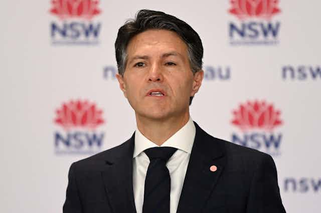 NSW MP Victor Dominello speaks at a press conference, and appears to have a 'droopy eye'.