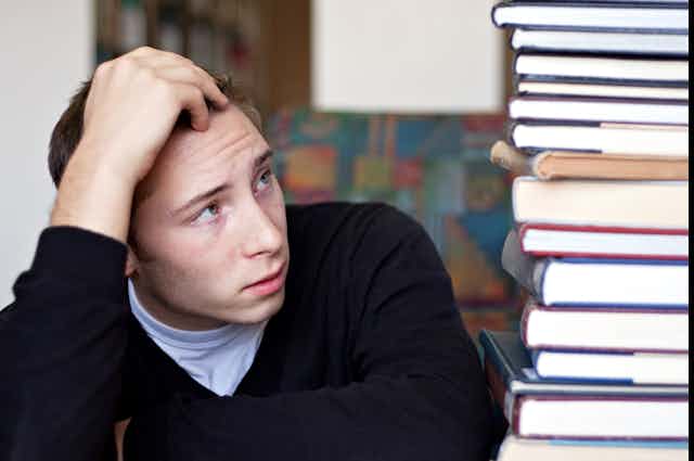 Students looks at daunting pile of books to be read