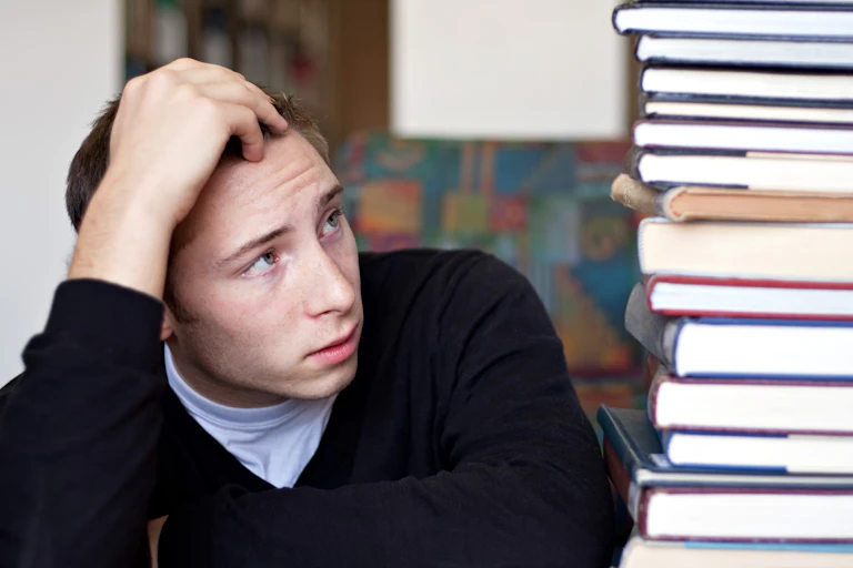 Students looks at daunting pile of books to be read