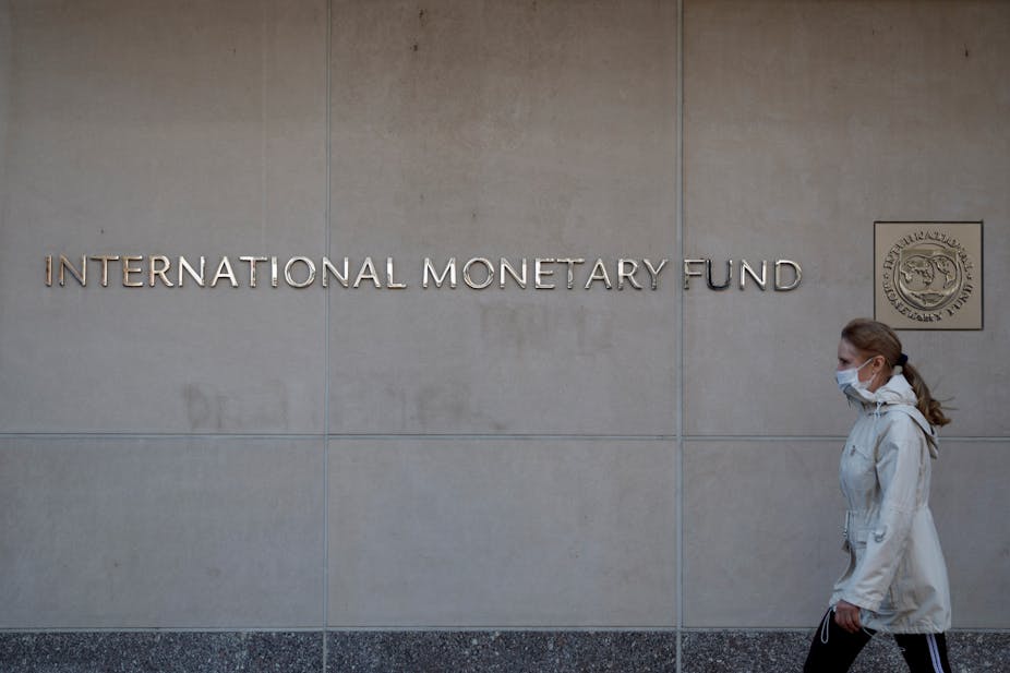A woman walks past IMF headquarters in Washington D.C.