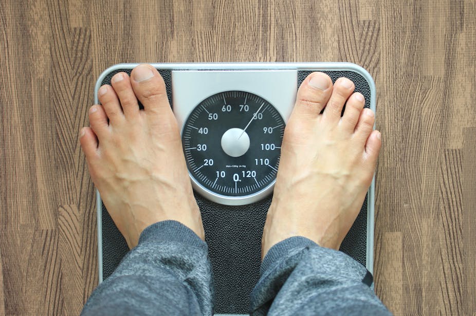 A person with bare feet stands on a scale to measure their weight.