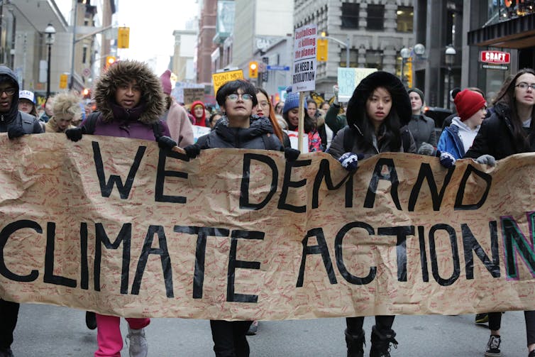Protesters carry a banner reading 'we demand climate action.'