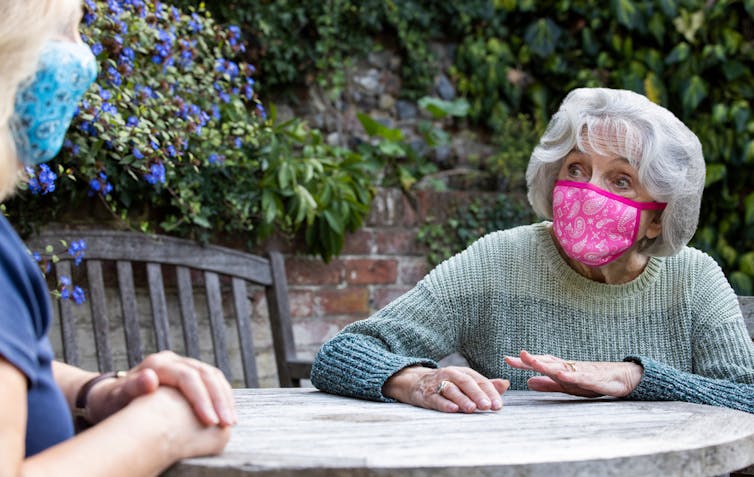 A social worker meeting someone outside, with both wearing masks.