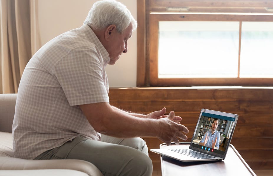 A senior man speaking to a social worker over a video call.