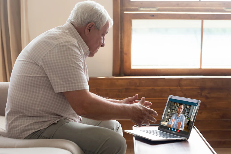 A senior man speaking to a social worker over a video call.