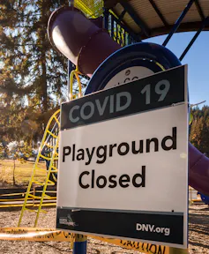 A sign attached to an outdoor play structure says 'COVID-19: Playground closed.'