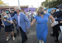 O'Toole holds hands with his wife who wears a blue dress.