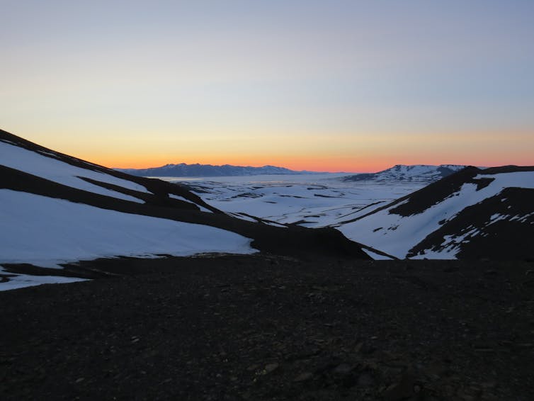 Outlook across empty snowy mountains and valleys at sunset