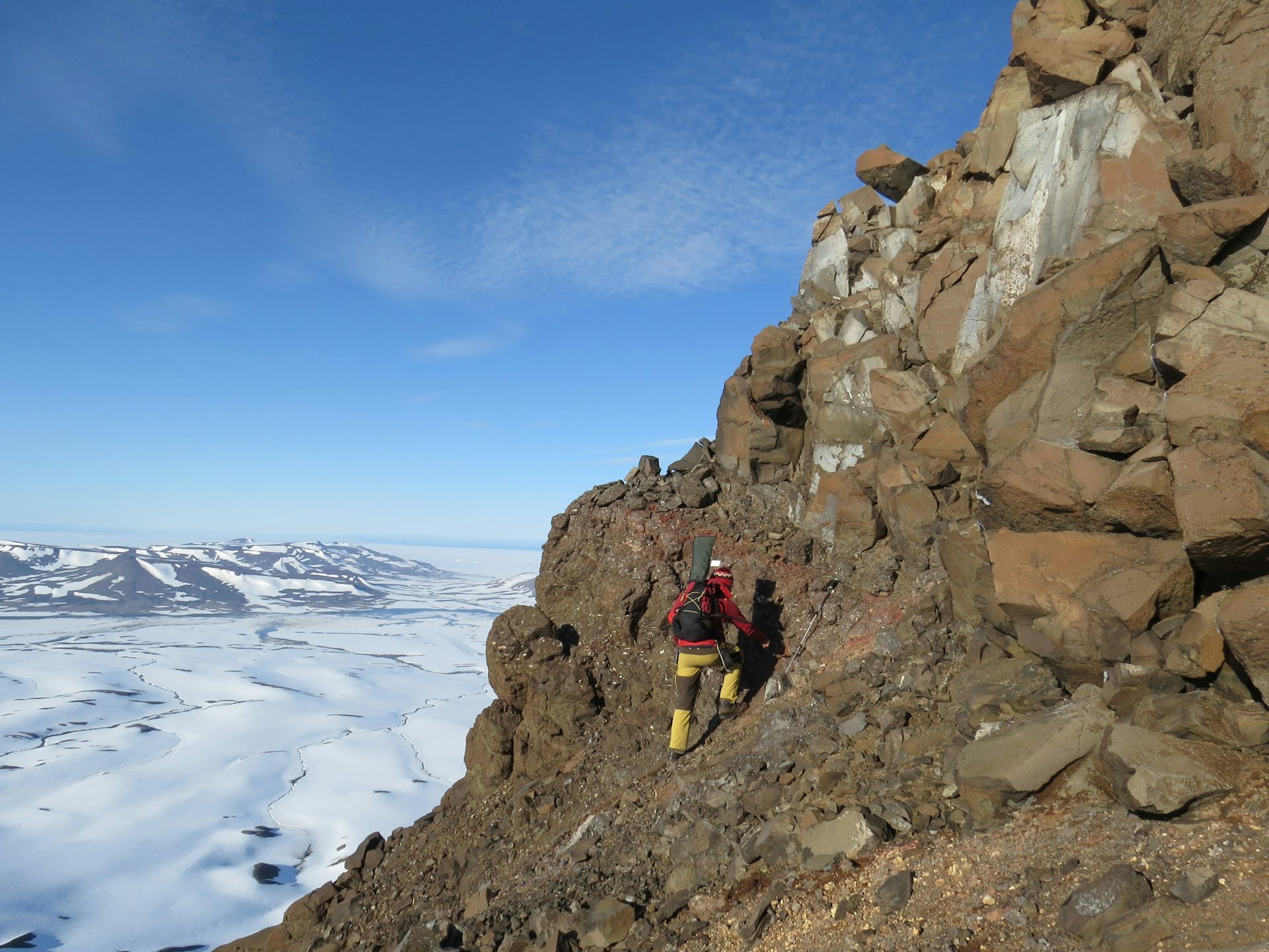 Geologist inspecting a cliff section exposing a volcanic sequence with evidence for subaerial eruptions in a tropical climate.