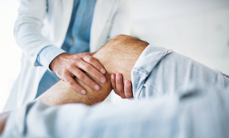 Health care provider holding a person's bent leg below the knee.