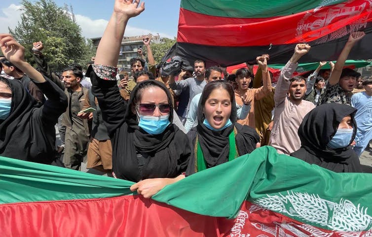 A group of protesters march with Afghan flags