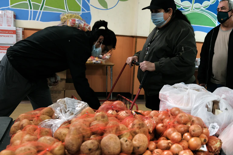 People in masks line up at a food pantry.