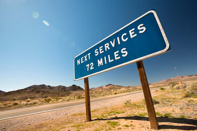 A road sign on a dry, desolate stretch reading "next services 72 miles"