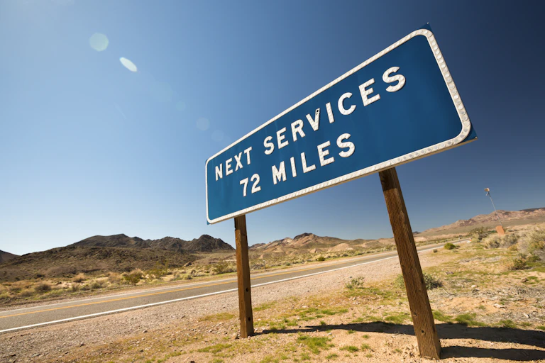 A road sign on a dry, desolate stretch reading "next services 72 miles"