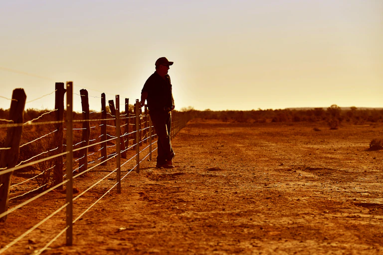 farmer leans on fence