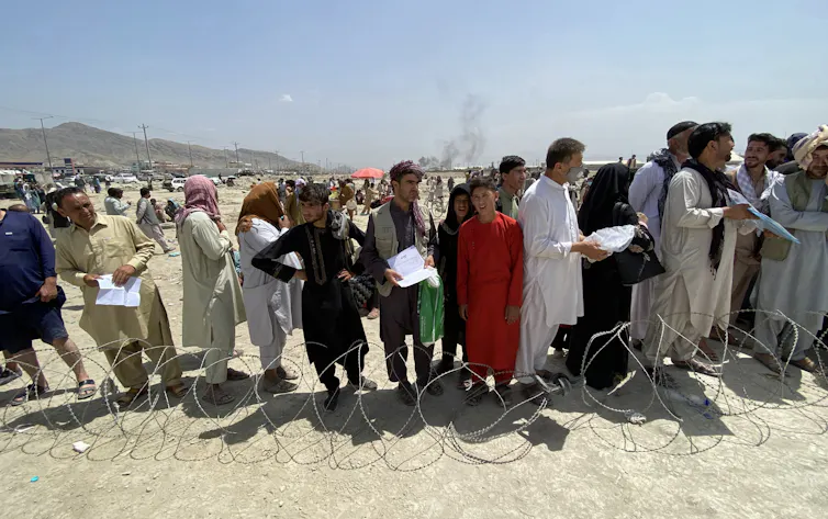 Afghans wait outside the Kabul airport to flee the country.
