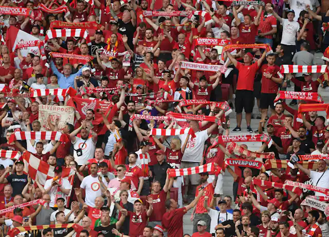 Liverpool fans wave scarves at a match.