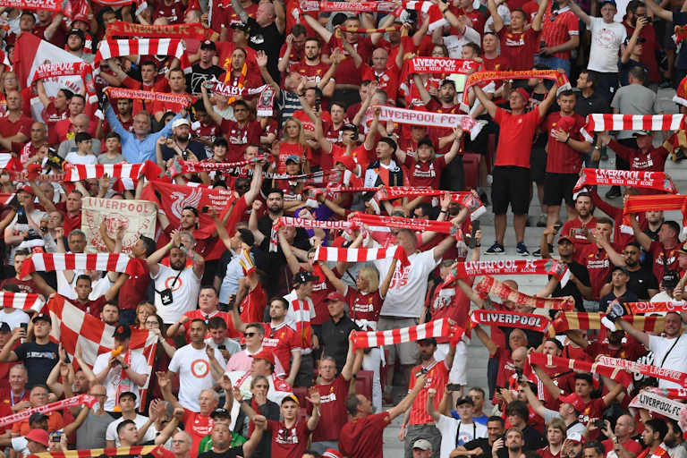 Liverpool fans wave scarves at a match.