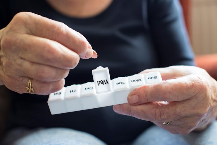 A person opening a pill box.