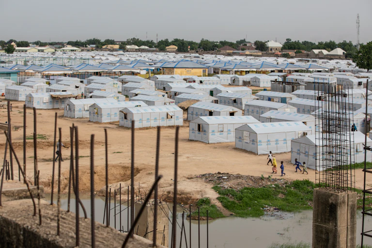 An aerial view of an internally displaced persons camp: rows of white tent structures