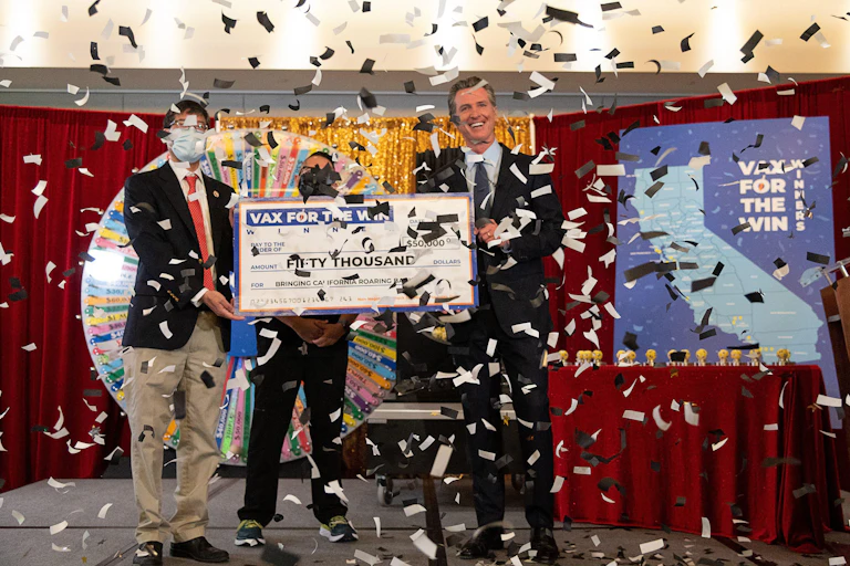 Governor Gavin Newsom holds a mock-up check for the first 15 Californians to be awarded US$50,000 for doing their part in getting vaccinated against COVID at the California Lottery Headquarters in Sacramento.