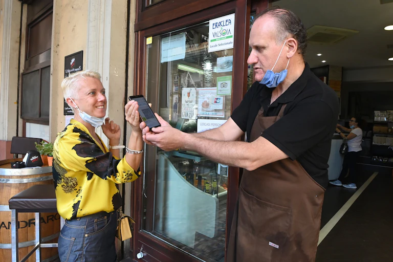 A customer shows the green pass to a staff member before entering the indoor dining area of a restaurant in Bologna, Italy, on Aug. 6, 2021.