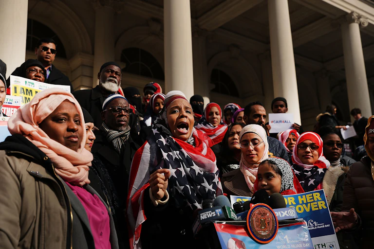 women wearing headscarfs and men gather in front of a building