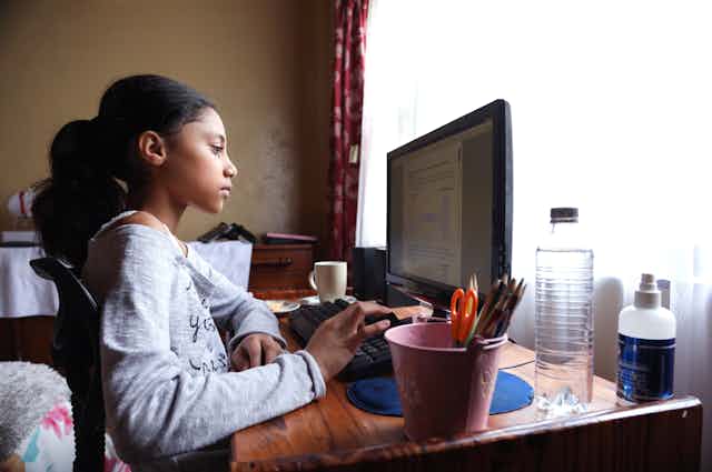 Girl sits at desk working on a computer