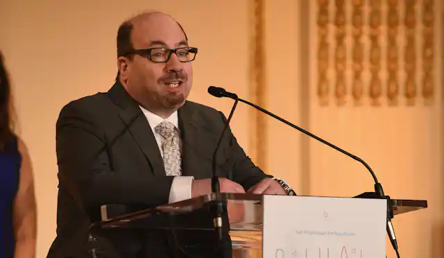 Craigslist founder Craig Newmark speaks at a podium.
