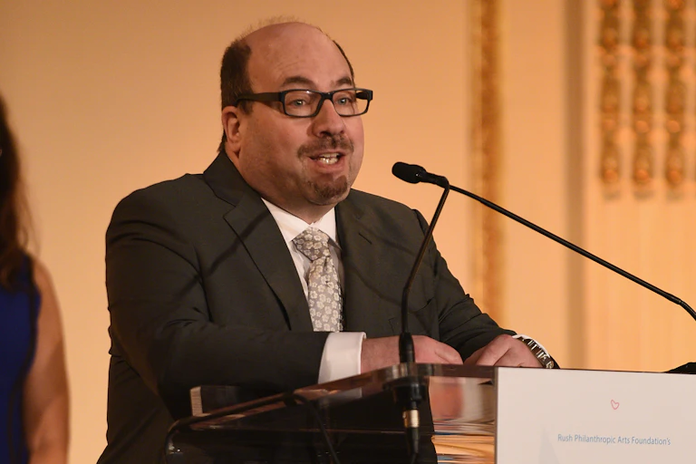 Craigslist founder Craig Newmark speaks at a podium.