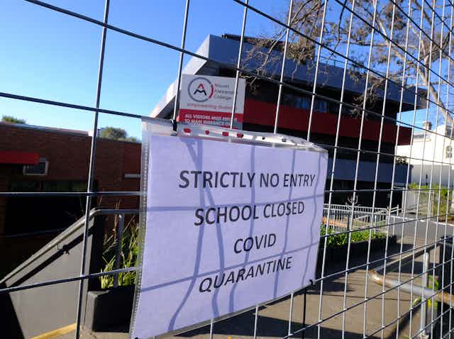 sign on school gate announces closure because of COVID-19 cases