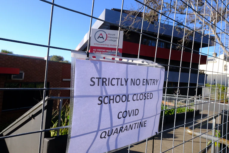 sign on school gate announces closure because of COVID-19 cases