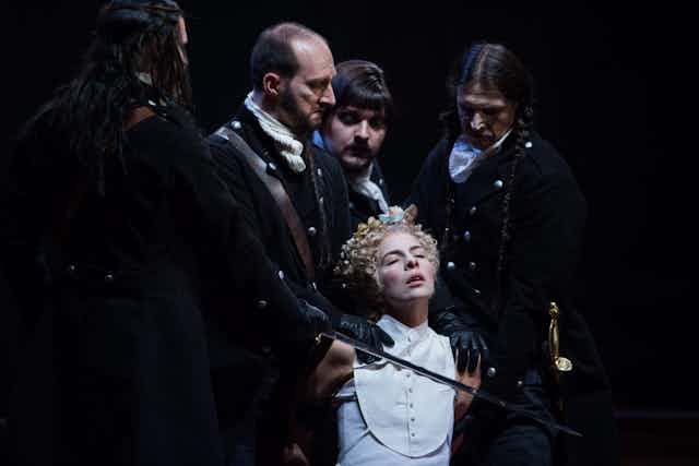 Opera production: a woman surrounded by men