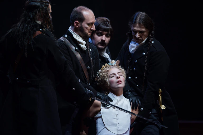 Opera production: a woman surrounded by men