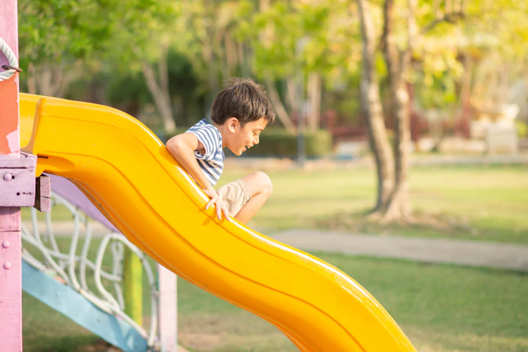 Boy going down slide on playground.