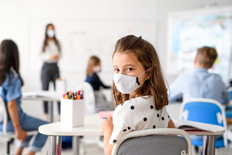 A girl in a classroom wearing a mask.