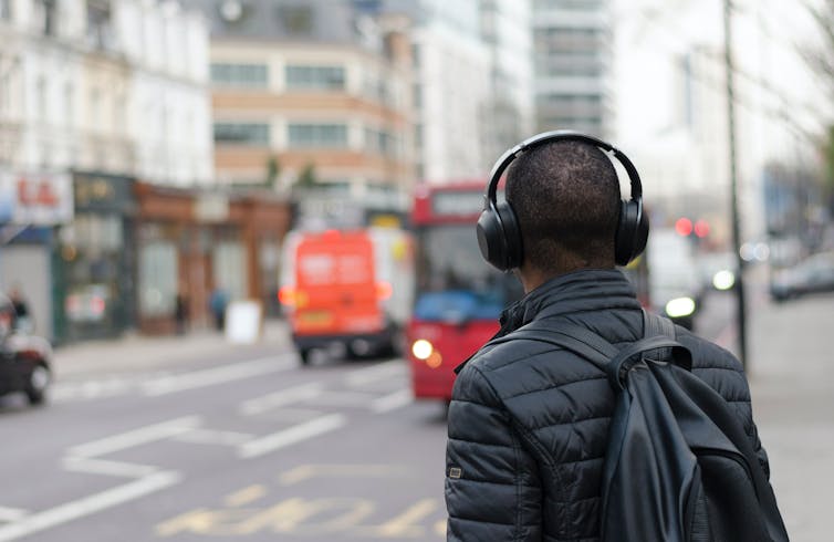 person with headphones waiting for a bus